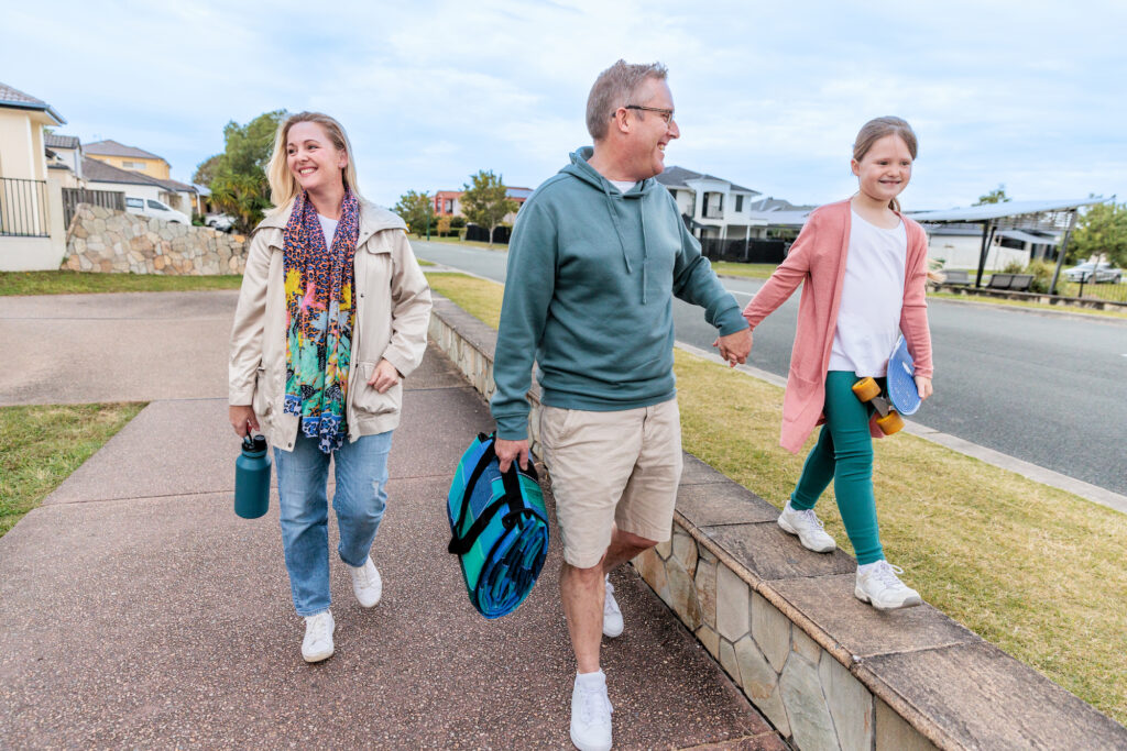 Mother, father and daughter walking along a path in a residential area