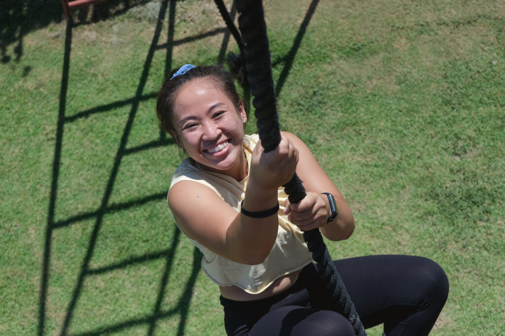 Active woman smiling and climbing up a rope