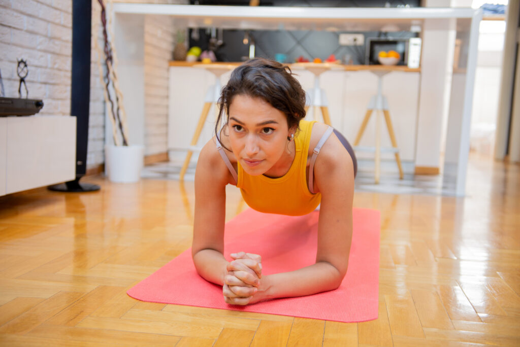 Woman in activewear doing a plank on a mat inside a modern home