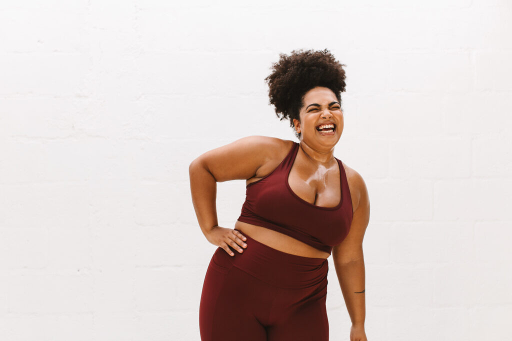 Woman in active gear laughing after completing a workout