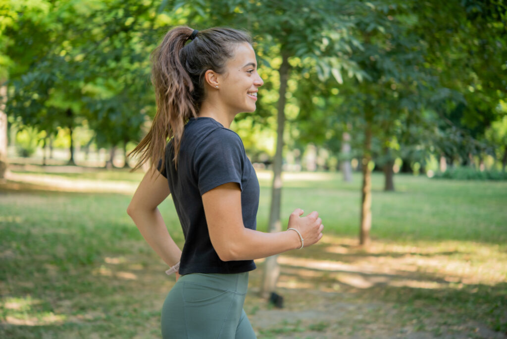 Young woman smiling and running in a sunny park