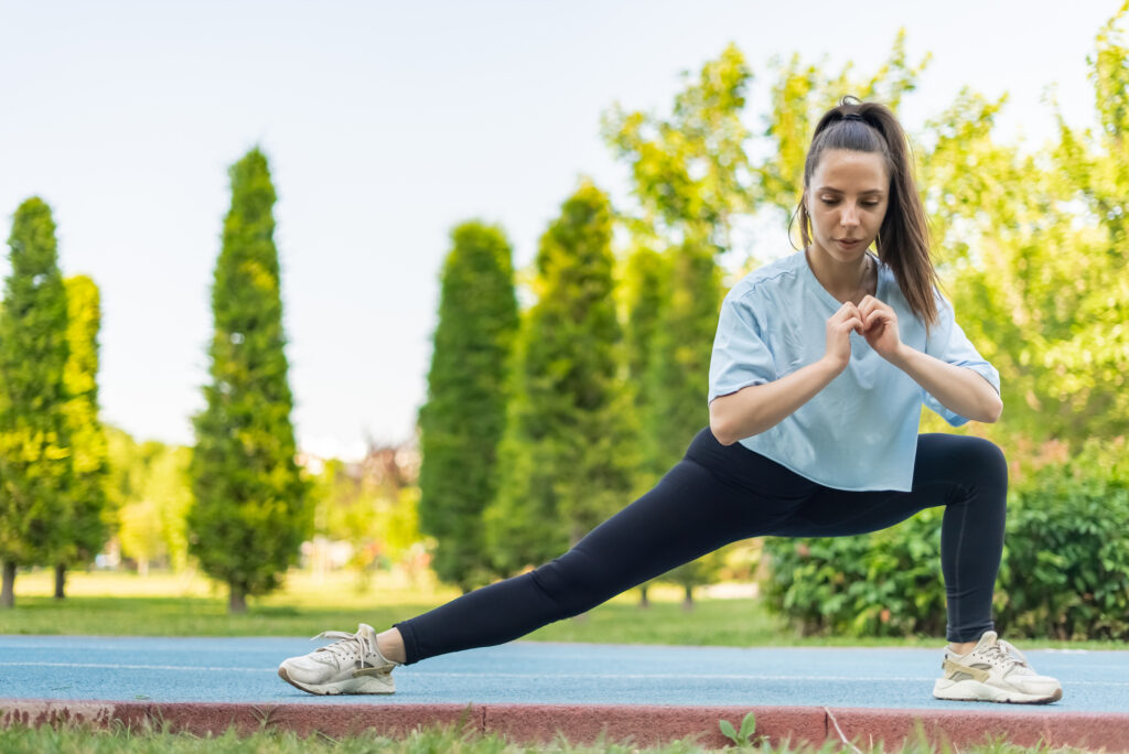 Active woman squatting and stretching her right leg in the park