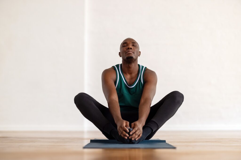 Man sitting on a mat while doing a yoga pose