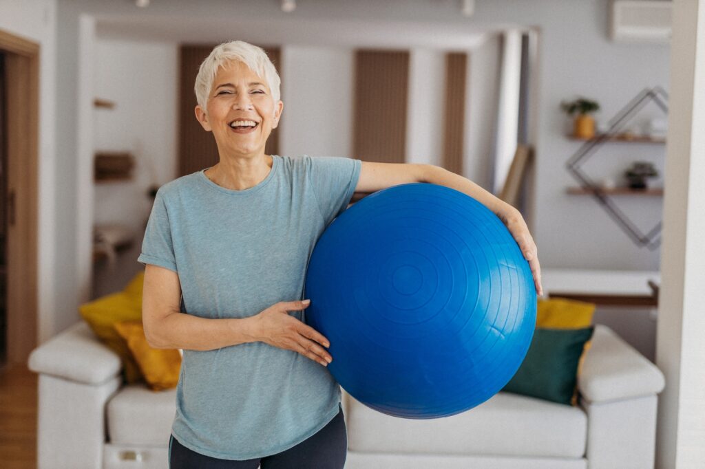 Senior woman holding a blue fitball and smiling