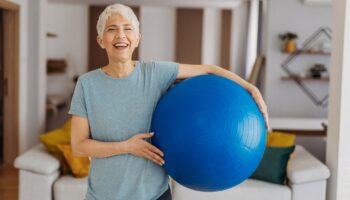 Senior woman holding a blue fitball and smiling