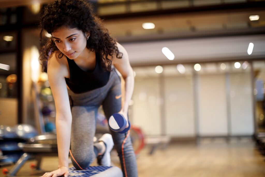 Young woman in gym rehabilitation doing a dumbbell row